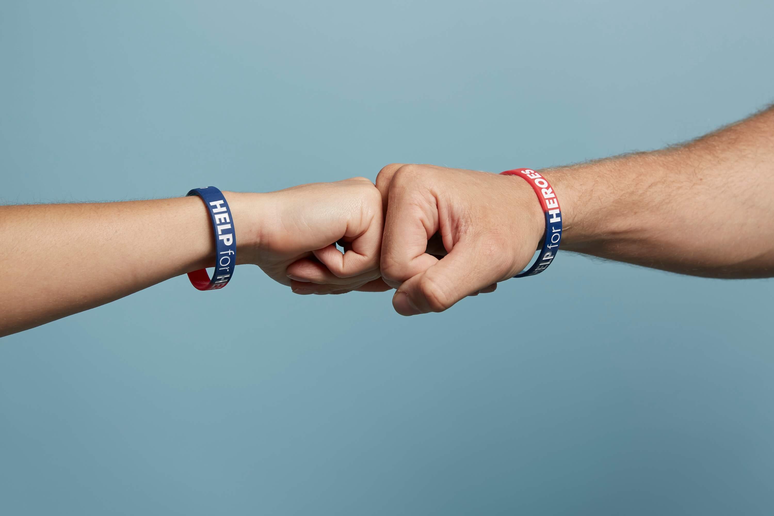 Two people giving each other a fist bump. Both are wearing Help for Heroes wristbands